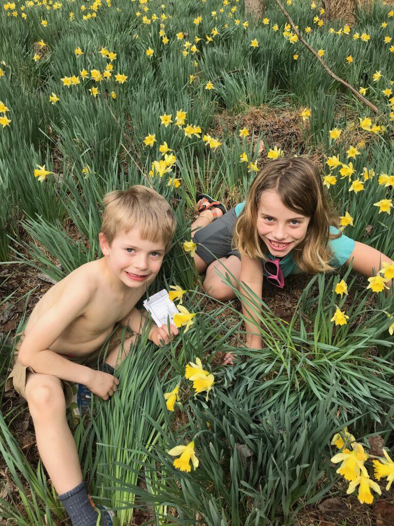 Ryan's daughter and son as kids, grinning from a patch of yellow daffodils.