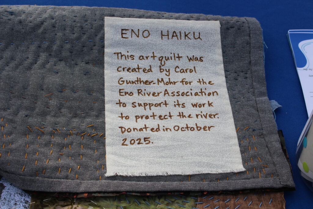 Note on the back of art quilt by Carol Gunther-Mohr. Reads: "Eno Haiku - This art quilt was created by Carol Gunther-Mohr for the Eno River Association to support its work to protect the river. Donated in October 2025."