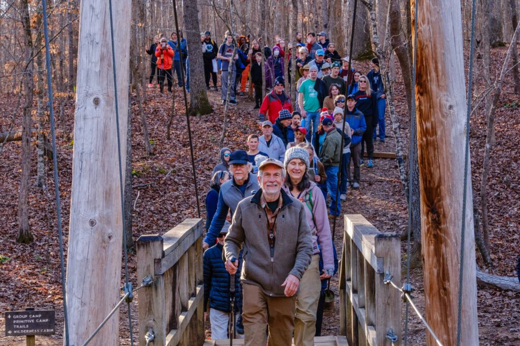 A crowd of Eno River lovers hikes together on New Year's Day 2024, enjoying the beautiful trails protected by advocacy efforts over the years.