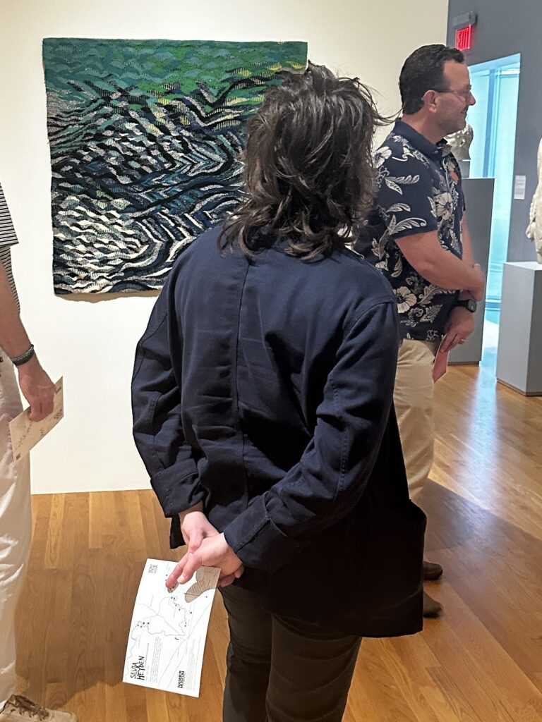 Heather McEntire of the Eno River Association holds a map of Silvia Heyden’s favorite spots along the Eno River while viewing one of her textile works inspired by the Eno on display at the Nasher Museum of Art at Duke University.